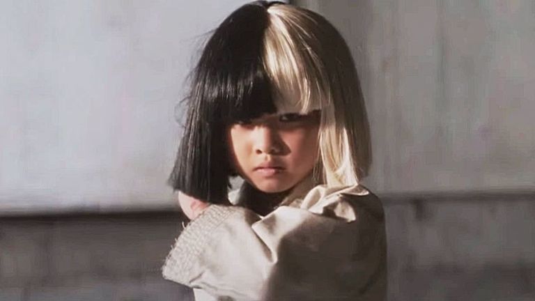 A young girl stood in a karate pose wearing a wig (half black, half white).