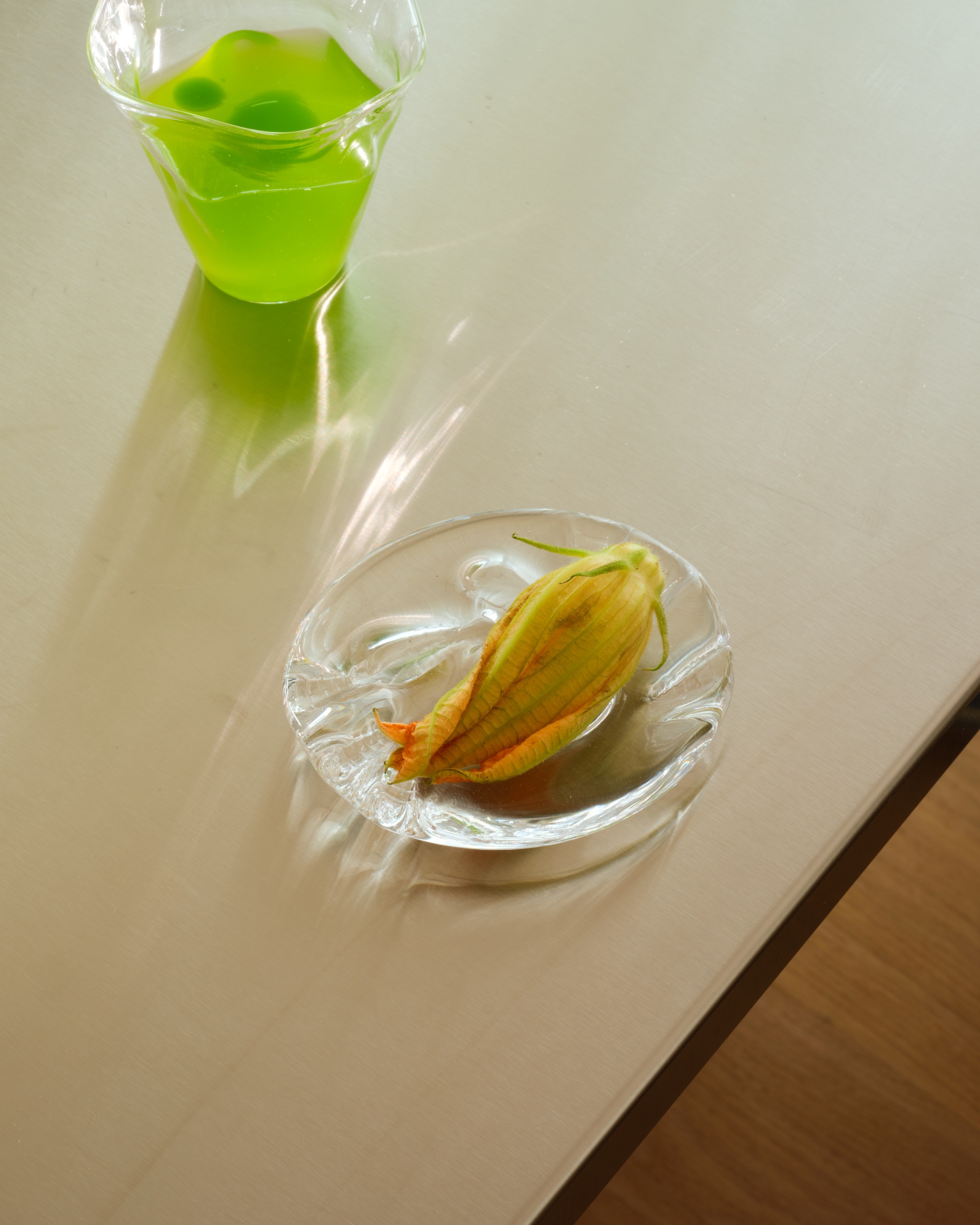 Still life shots of a restaurant interior featuring glossy round tables, leather chairs in black, chrome tabletops, and essentially presented food.