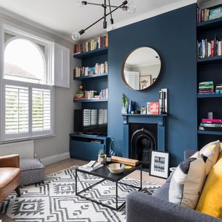 living room with blue wall book shelf on wall white window and sofa