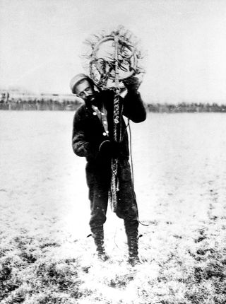 Albert Berry carries his parachute on his shoulder. He was the first person to jump from a plane with a parachute, 1912.