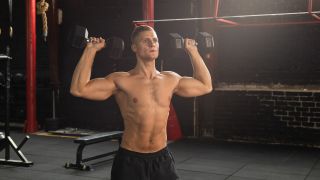 Man holding dumbbells by his shoulders