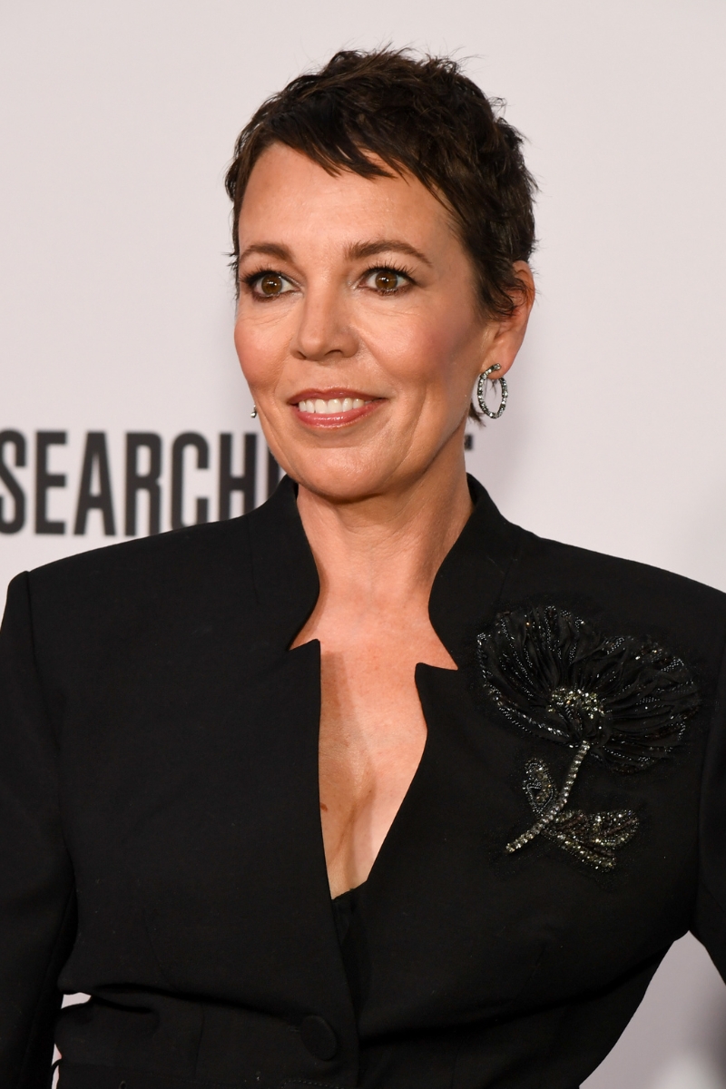 Olivia Colman is pictured with a pixie cut hairstyle and wearing a black blazer, with a flower embellishment at "The Roses" New York Premiere held at The Hudson Theater on August 25, 2025 in New York, New York.