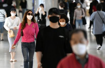 People wearing face masks walk through an underground shopping area in Seoul on May 6, 2020