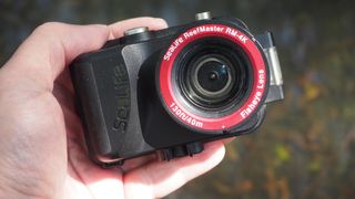 SeaLife ReefMaster RM-4K camera held in a hand over some water