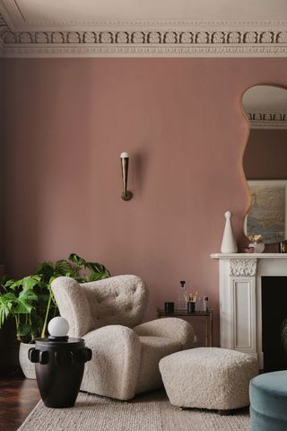 pink living room with boucle armchair and footstool