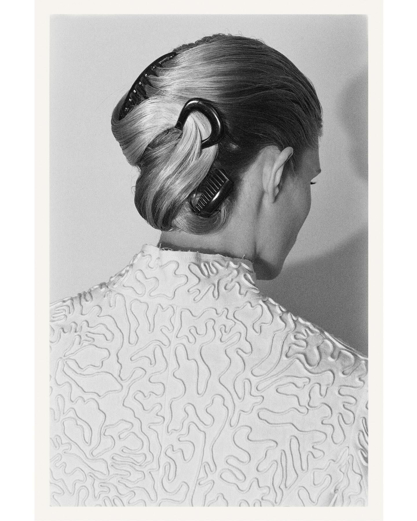 A model at The Row with an updo and multiple French combs and pins in her hair