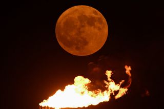 A Super Blue Moon rises over the flare stacks of an oil field near the southern port city of Basra on August 19, 2024