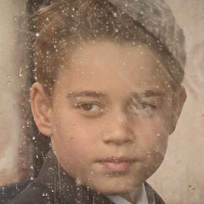 Prince George looks through a dirty carriage window and he stands on Buckingham Palace balcony wearing a suit alongside younger brother Prince Louis