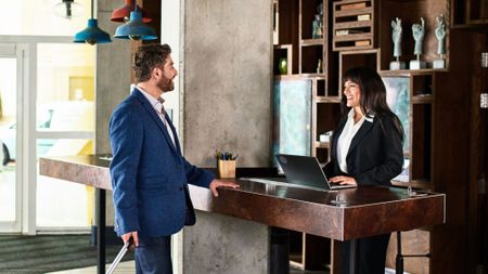 Businessman with suitcase arriving at hotel reception