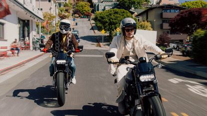Two people riding the Harley Davidson LiveWire S2 Del Mar on a suburban street