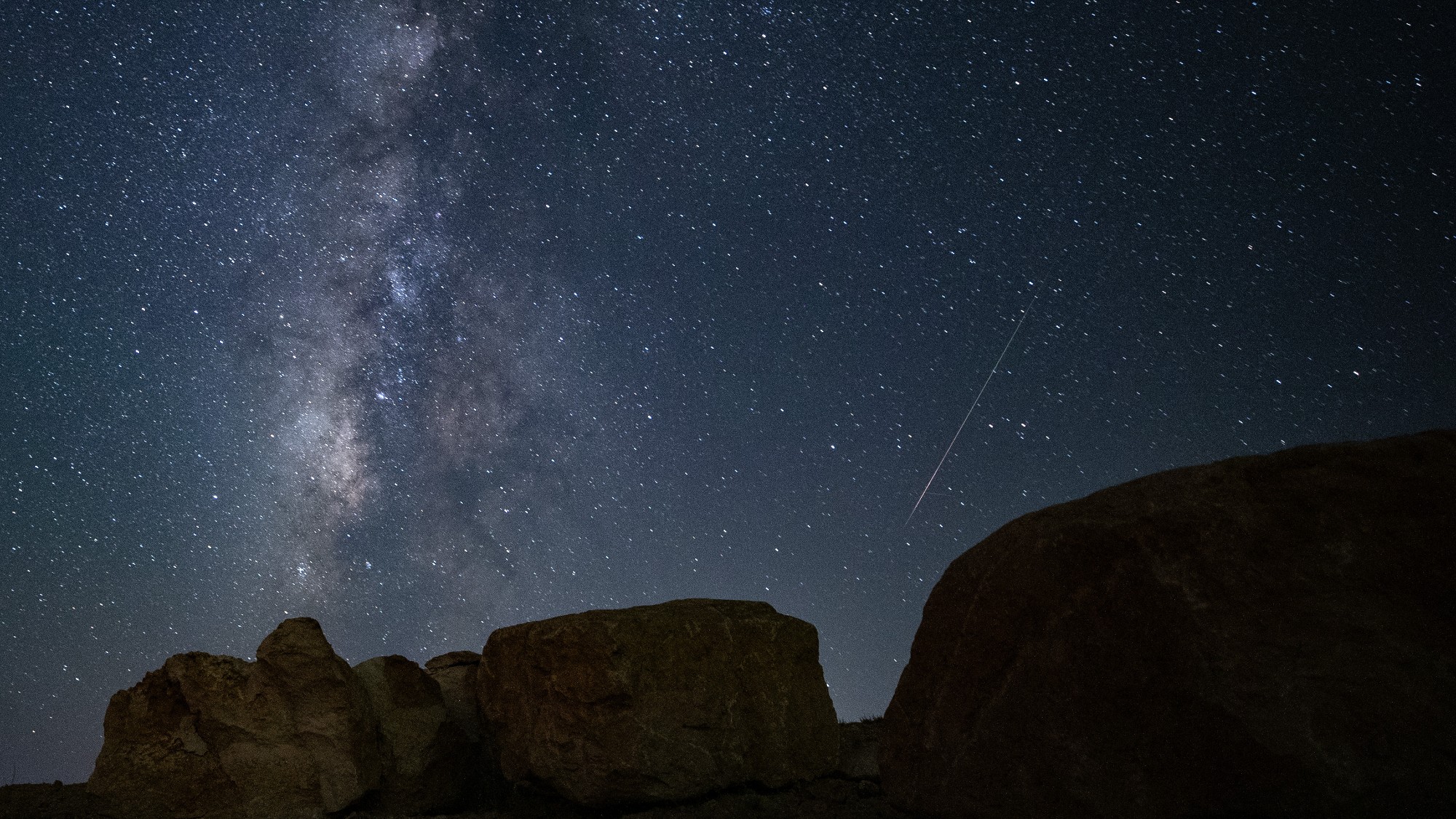 a streak of light crosses through the night sky