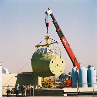 The crew module is being lowered into the vacuum chamber test facility at the Rockwell Downey facility on January 20, 1987.