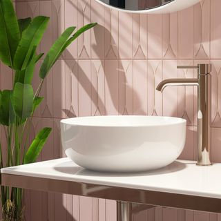 pink bathroom tiles and a white modern sink with a nearby plant