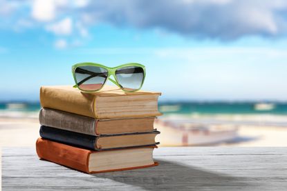 Books and sunglasses on beach background