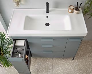 A bathroom vanity with a pulled out tall drawer