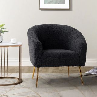 A black Dawson Upholstered Barrel Chair in a modern living room next to a side table