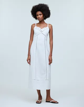model wears white dress with detailing on the neckline and flip flop type sandals