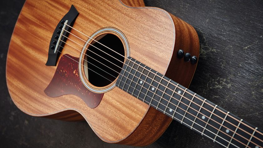 A Taylor GS Mini acoustic guitar lying on a wooden floor