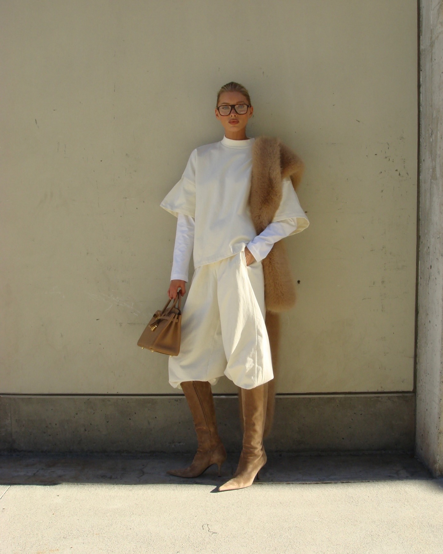 Elsa Hosk wearing a butter yellow sweatshirt and sweatpants with tan boots, a tan fur scarf, and a tan Birkin bag.
