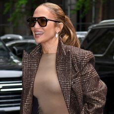 Jennifer Lopez wears a brown skirt and brown boots