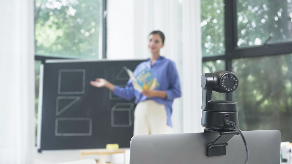 Woman presenting at blackboard with monitor-mounted Obsbot webcam in the foreground