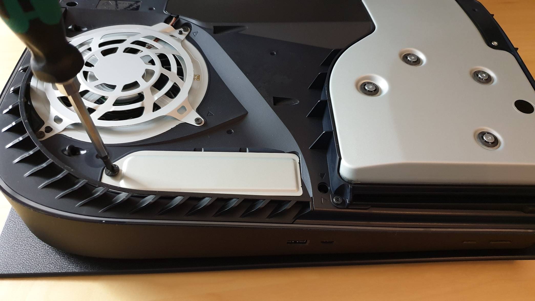 Die Schraube des SSD-Schachts der PS5 wird mit einem Schraubenzieher entfernt