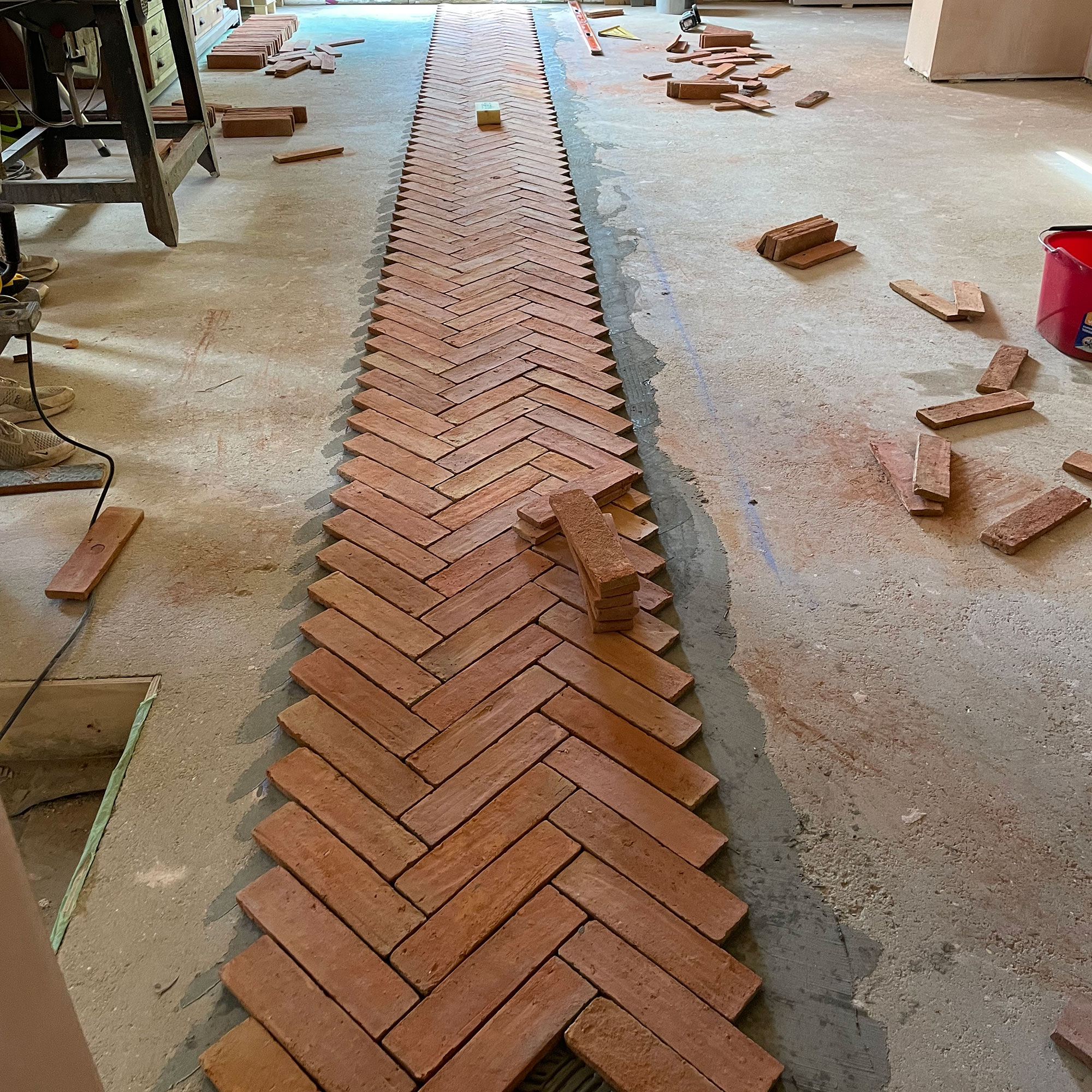 Terracotta floor tiles being laid out in parquet pattern