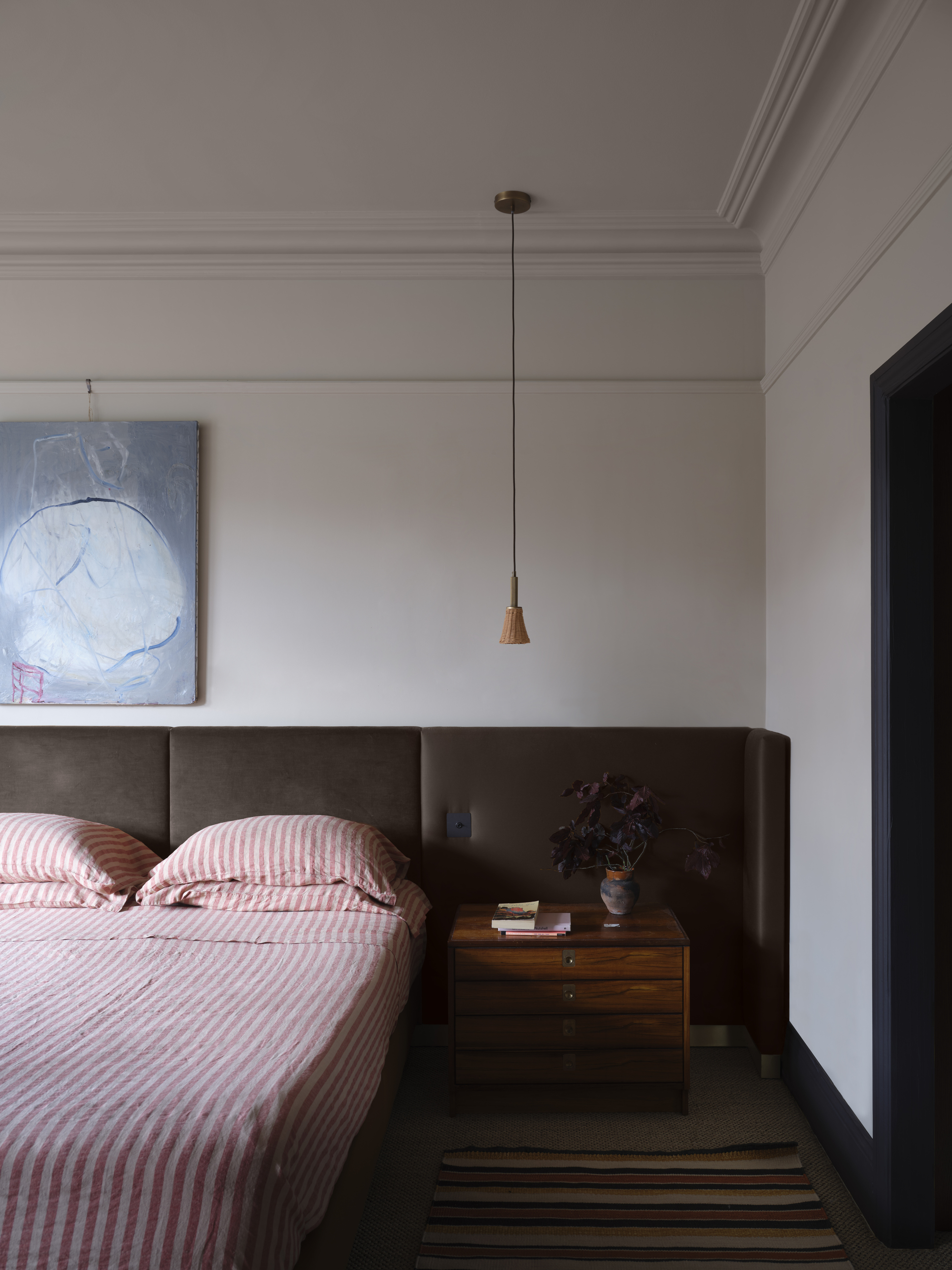 A mid-century style bedroom with a large brown headboard and red and white striped bedding