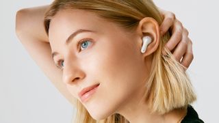 A woman pulling back her hair to show the LG Tone Free FP8 earbud in white in her left ear