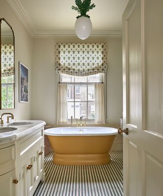 vintage style bathroom with striped tile floor and a yellow painted freestanding bath tub