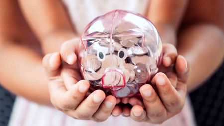 parent and kid holding piggy bank