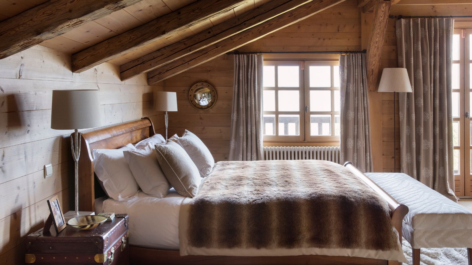 A wooden panelled attic conversion with a rustic bed. 