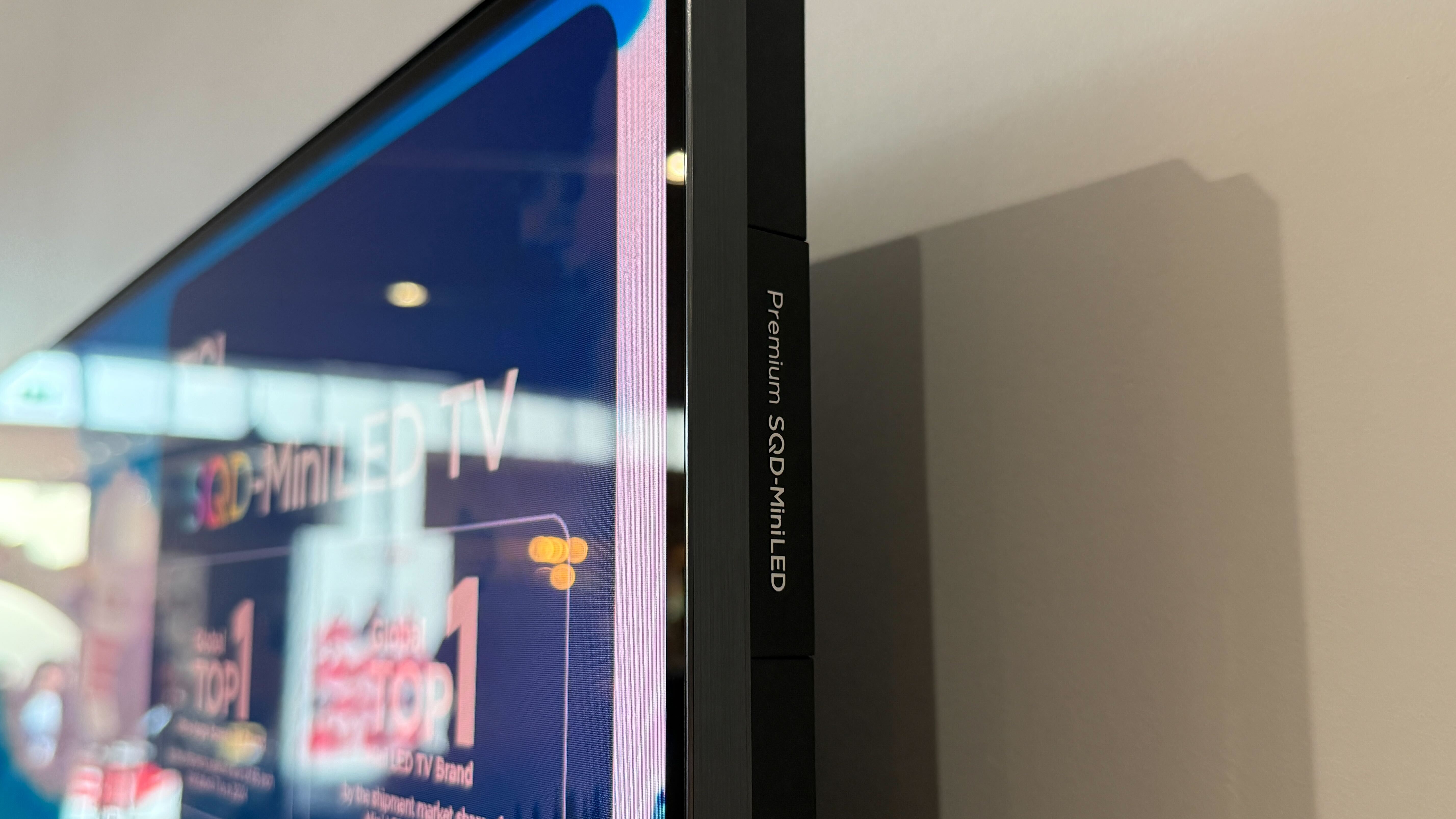 Wall-mounted TCL C7L with vibrant demo content on screen