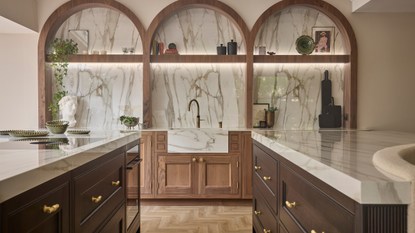 traditional kitchen with gold hardware, arched wooden cabinets and marble counters