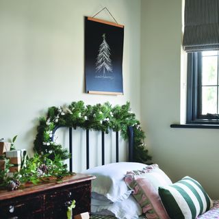 A bedroom decorated for Christmas with a drawing of a Christmas tree hanging above the bed