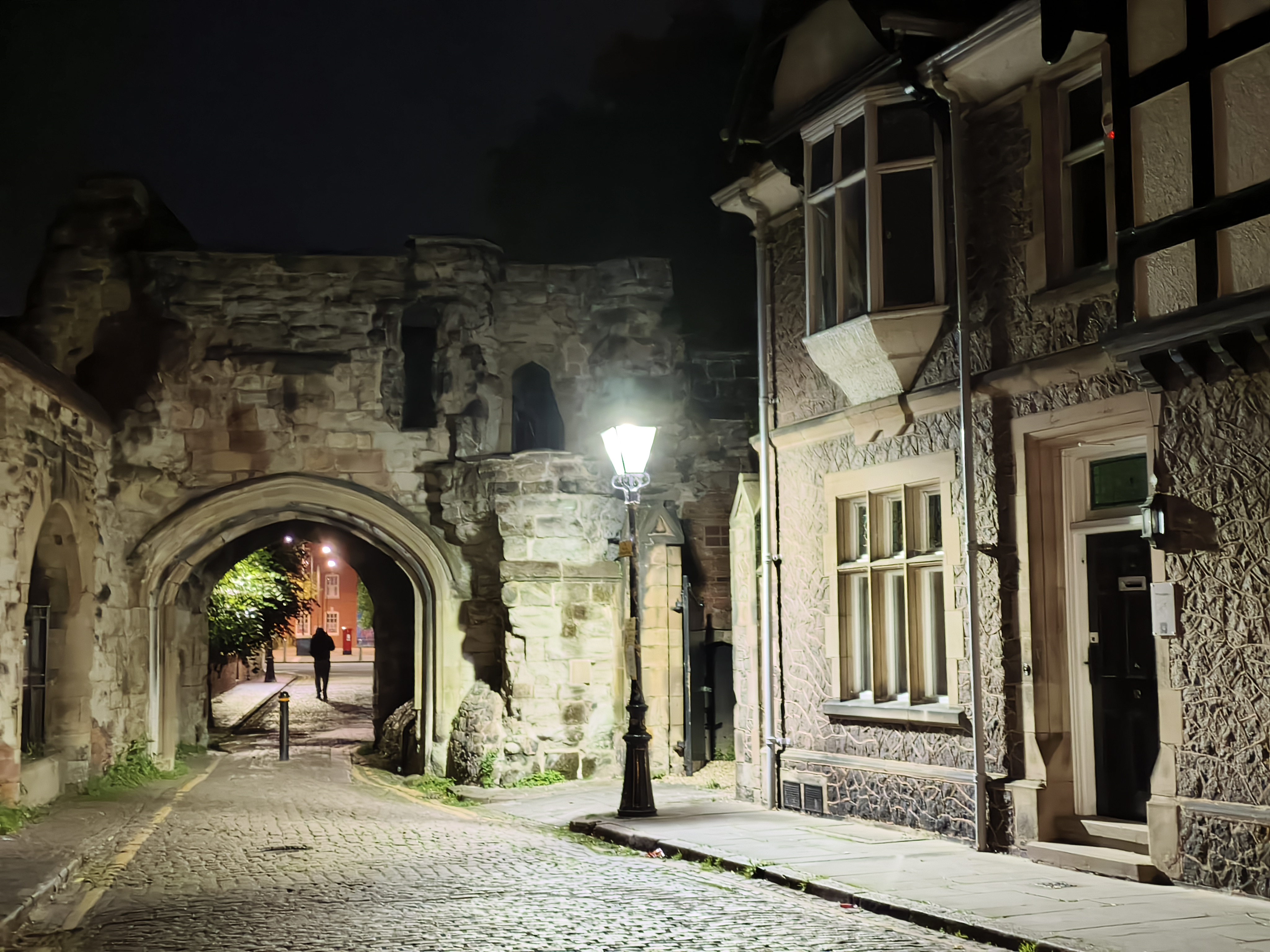 Cobbled Street in England with an old building let up at night by a street lamp