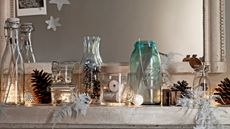 Christmas mantel decorated with pine cones in glass jars