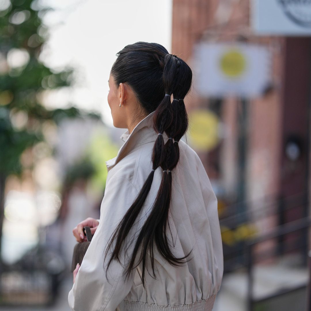 Woman wears beige trench and high bubble ponytail - best k-beauty hair products