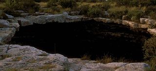 a large dark sinkhole surrounded by rocks