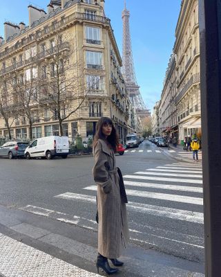 Woman wearing wool wrap coat, standing on Parisian street.