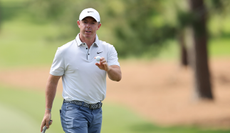 Rory McIlroy waves to the crowd holding a golf ball
