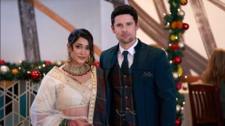 Anuja Joshi in a white saree and Benjamin Hollingsoworth in a blue tartan suit, smiling arm in arm in Christmas with the Sighs