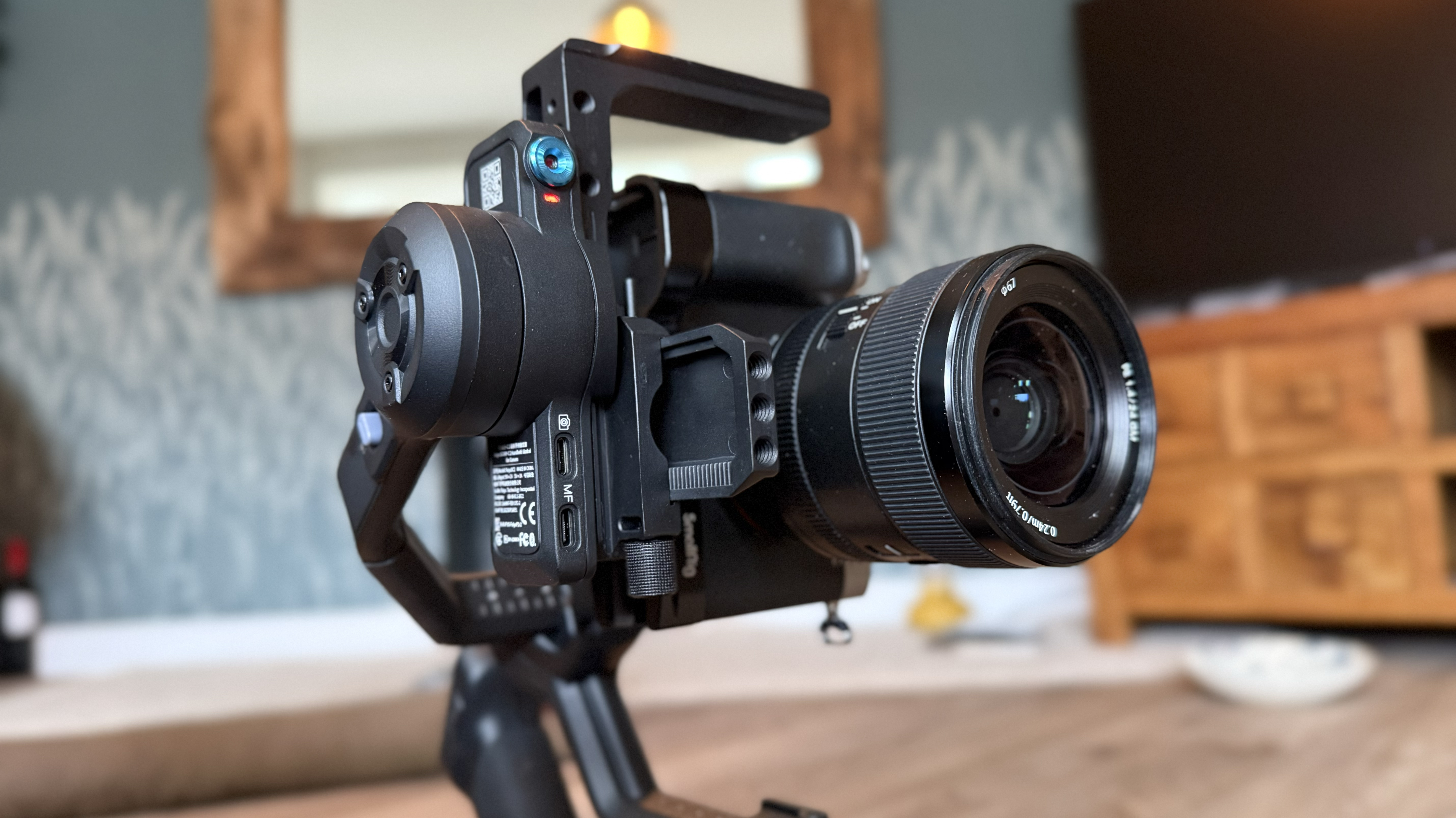 Camera mounted vertically on a handheld gimbal with a lens attached indoors