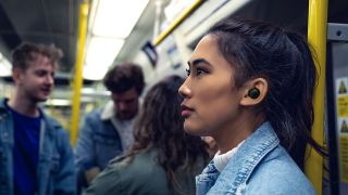 A woman wearing Sensemore Air earbuds in a subway carriage