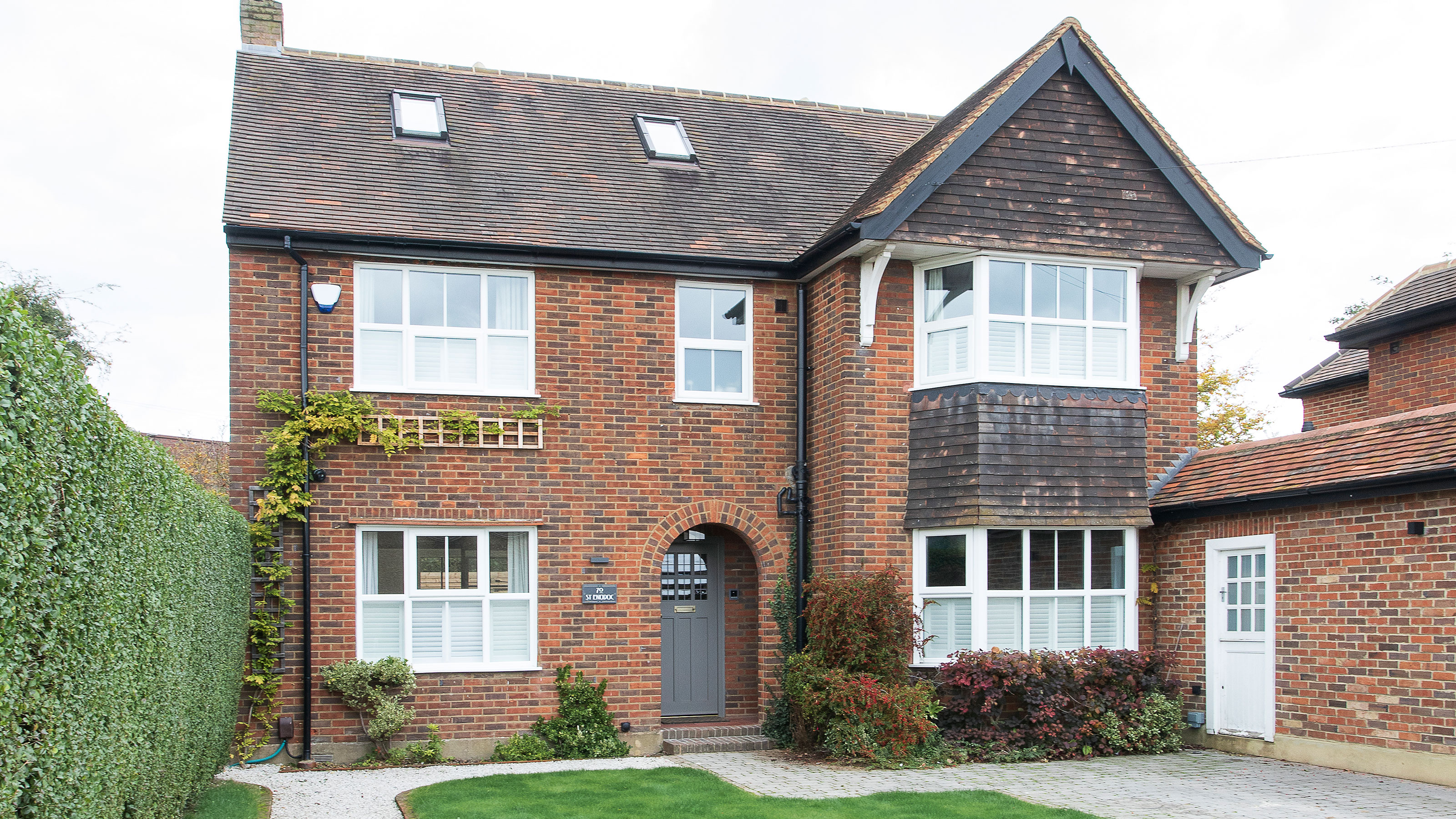 Brick house with grey roof and white window frames