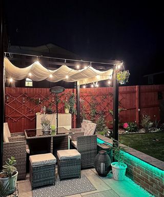 A patio with a pergola and garden furniture adorned by bright light bulbs