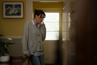 Becca (Suranne Jones) stands in the hallway of a house, leaning against a table for support and chewing nervously on a fingernail