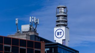 A cell tower bearing the BT logo, sat on top of a building. Decorative: The BT logo is in the brand's trademark purple, against the white of the cell tower. All are set against a blue sky.