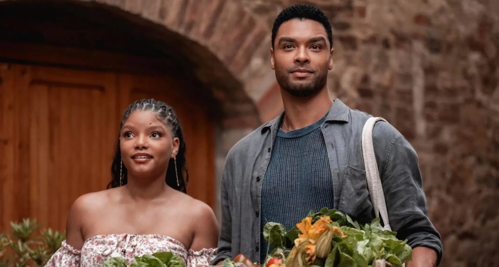 halle bailey and rege jean page looking out over a balcony covered in flowers in italy in a still from the movie you me and tuscany