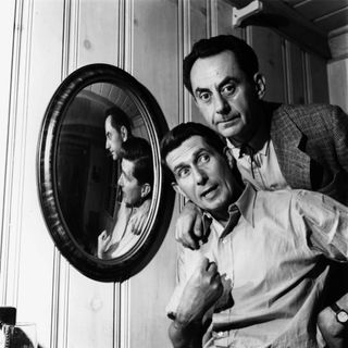 A portrait of Man Ray stood behind Roland Penrose with a mirror on the wall